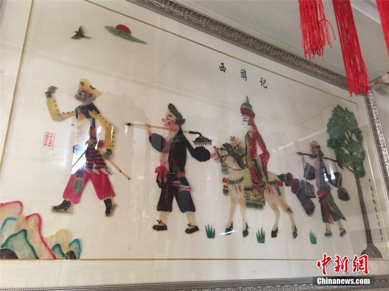 Китайский народный художник вырезает новые фигуры для театра теней