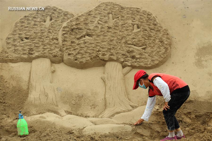 Мастера создают песчаные скульптуры на берегу реки Хуанхэ
