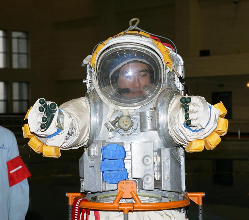 Первый китайский космонавт Чжай Чжиган проверяет составные части скафандра