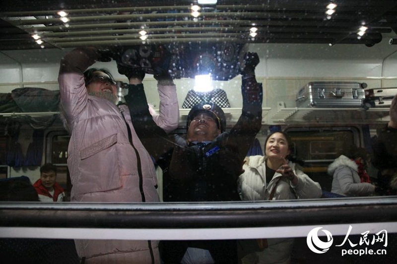 Ранним утром 1 февраля на первом поезде, следующем из Пекина в Чунцин в пик пассажирских перевозок по случаю праздника Весны в этом году, проводник помогает поставить чемоданы на верхнюю полку.