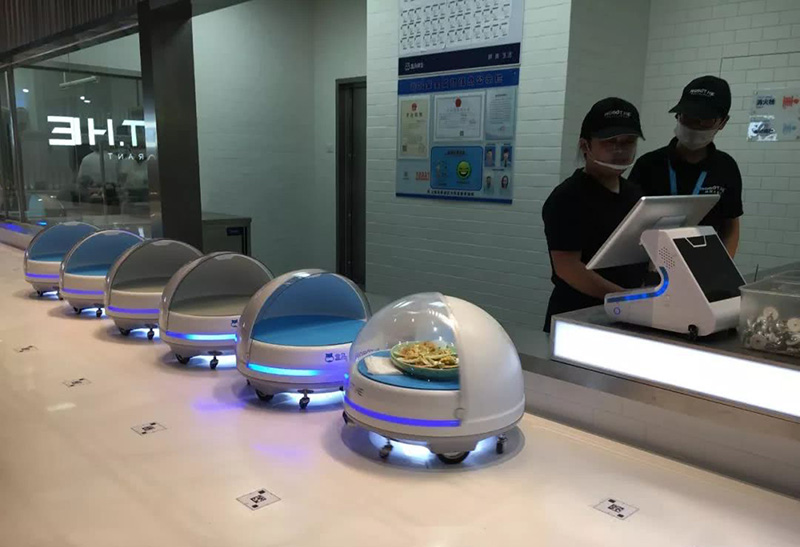 Роботы ждут готовых блюд перед их доставкой посетителям.